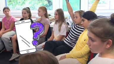 Kinder sitzen im Stuhlkreis, darauf ein Handy-Doodle und ein Fragezeichen in lila