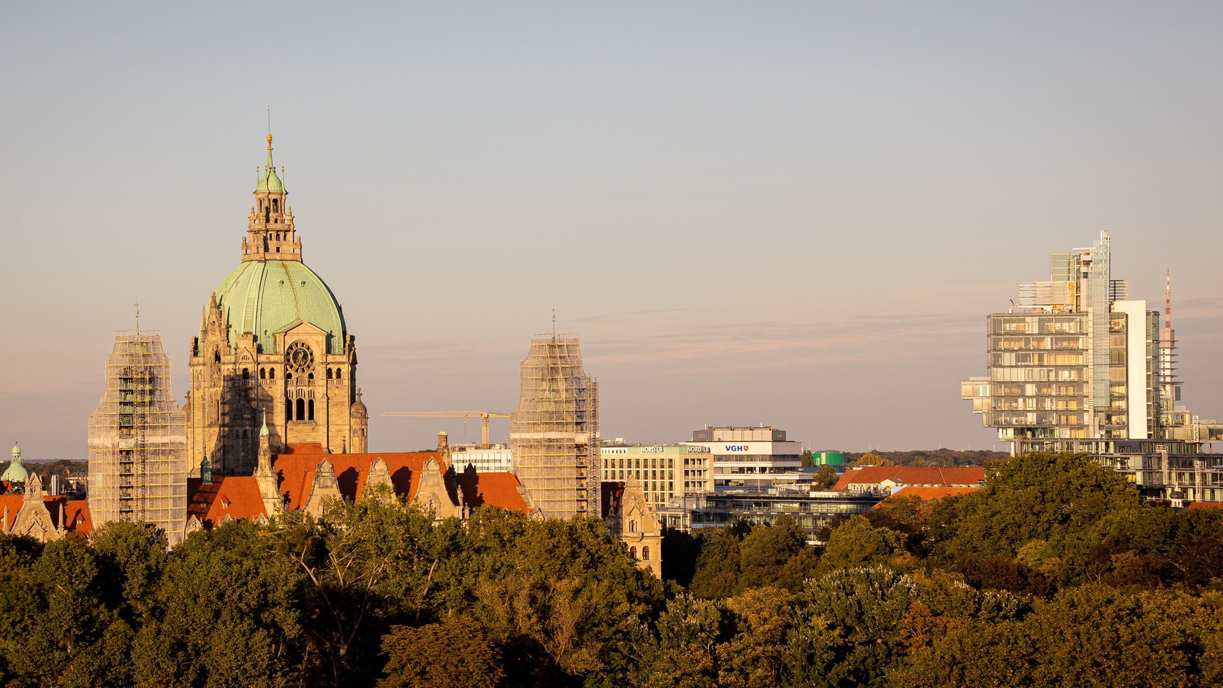 Das Neue Rathaus (l) steht im Licht der Herbstsonne hinter Bäumen neben dem Verwaltungsgebäude der Norddeutschen Landesbank (r). 