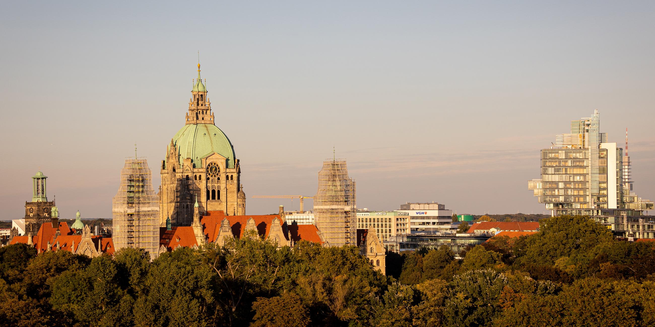 Das Neue Rathaus (l) steht im Licht der Herbstsonne hinter Bäumen neben dem Verwaltungsgebäude der Norddeutschen Landesbank (r). 