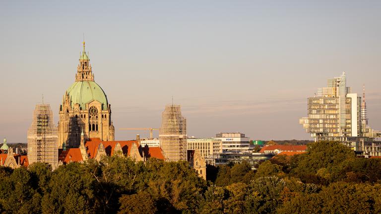 Das Neue Rathaus (l) steht im Licht der Herbstsonne hinter Bäumen neben dem Verwaltungsgebäude der Norddeutschen Landesbank (r). 
