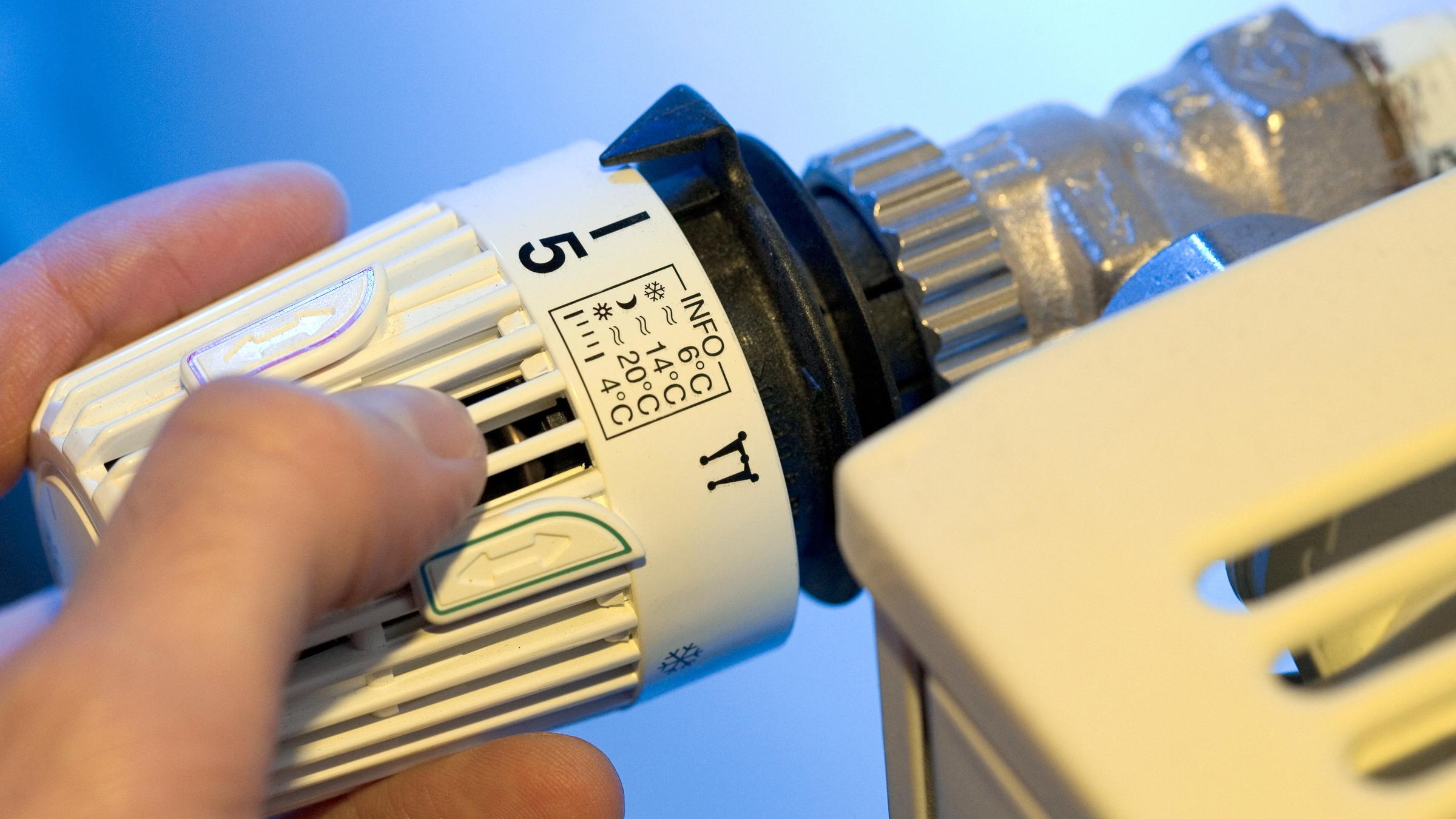 Heizkosten: Eine Hand dreht an demThermostat einer Heizung