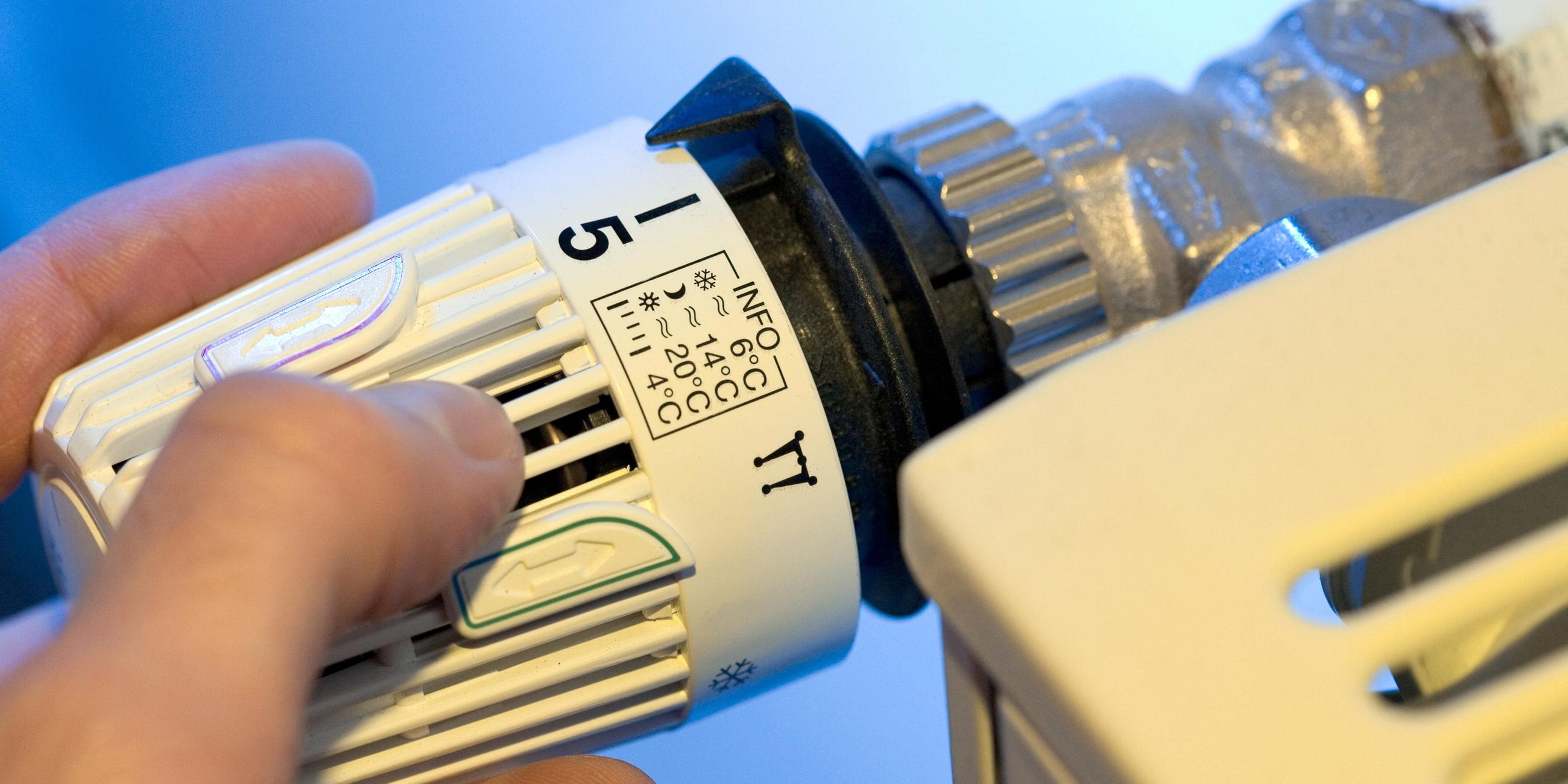 Heizkosten: Eine Hand dreht an demThermostat einer Heizung