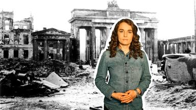 Reporterin Lotte vor einer Schwarz-Weiß-Fotografie des im Zweiten Weltkrieg zerstörten Brandenburger Tors.