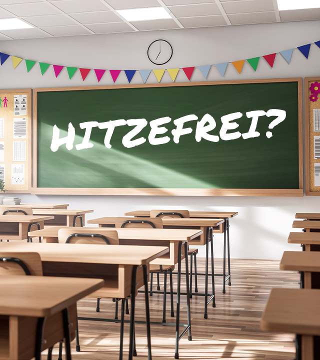 Ein leeres Klassenzimmer mit Blick auf die Tafel, darauf steht: Hitzefrei?
