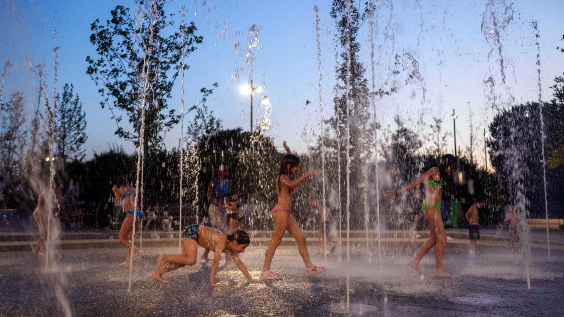 Kinder spielen in Wasserfontainen.  