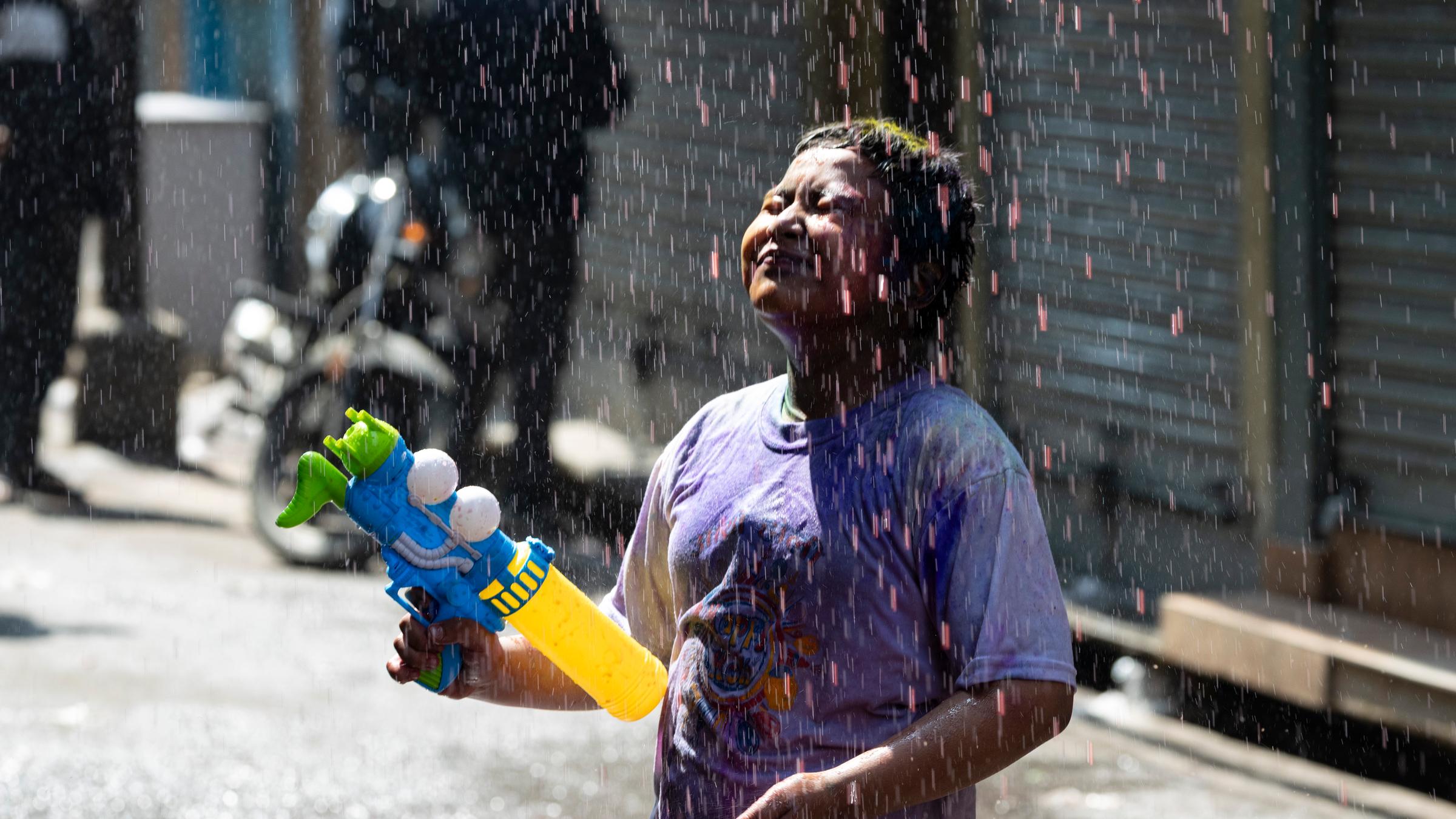 Kind steht im Farbregen während dem Holi Festival in Nepal