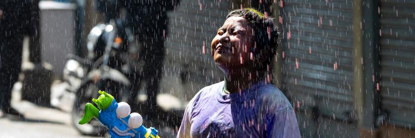 Kind steht im Farbregen während dem Holi Festival in Nepal