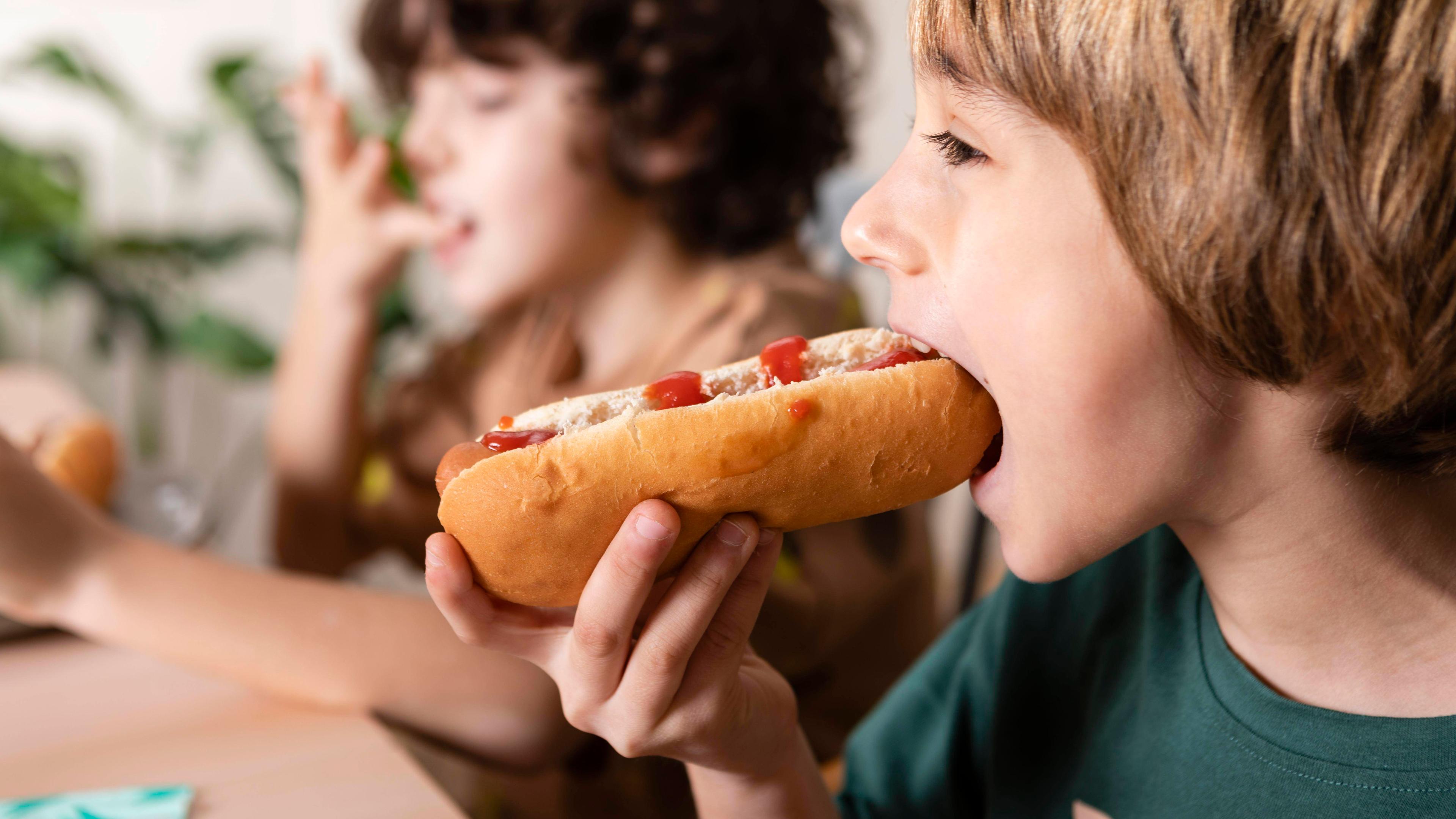 Junge isst einen Hotdog. 