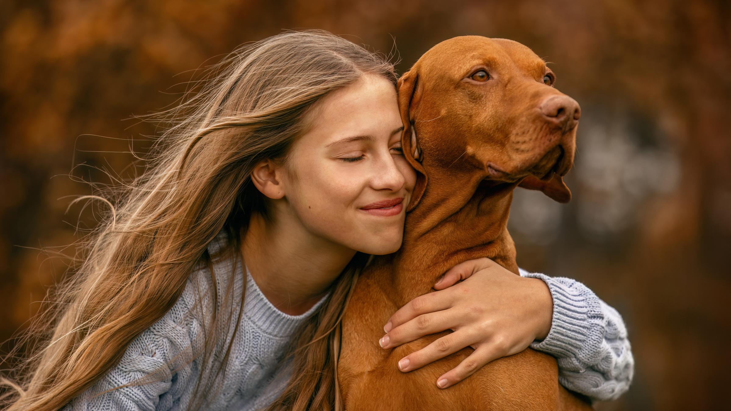 Mädchen kuschelt mit Hund.