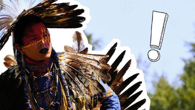 Mensch mit Federschmuck und Bemalung schaut zur Seite, hinter ihm blauer Himmel und Bäume.