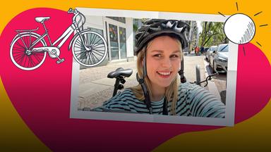 Isabelle mit einem Fahrradhelm und ihrem Farrad auf einer bunten Farbfläche