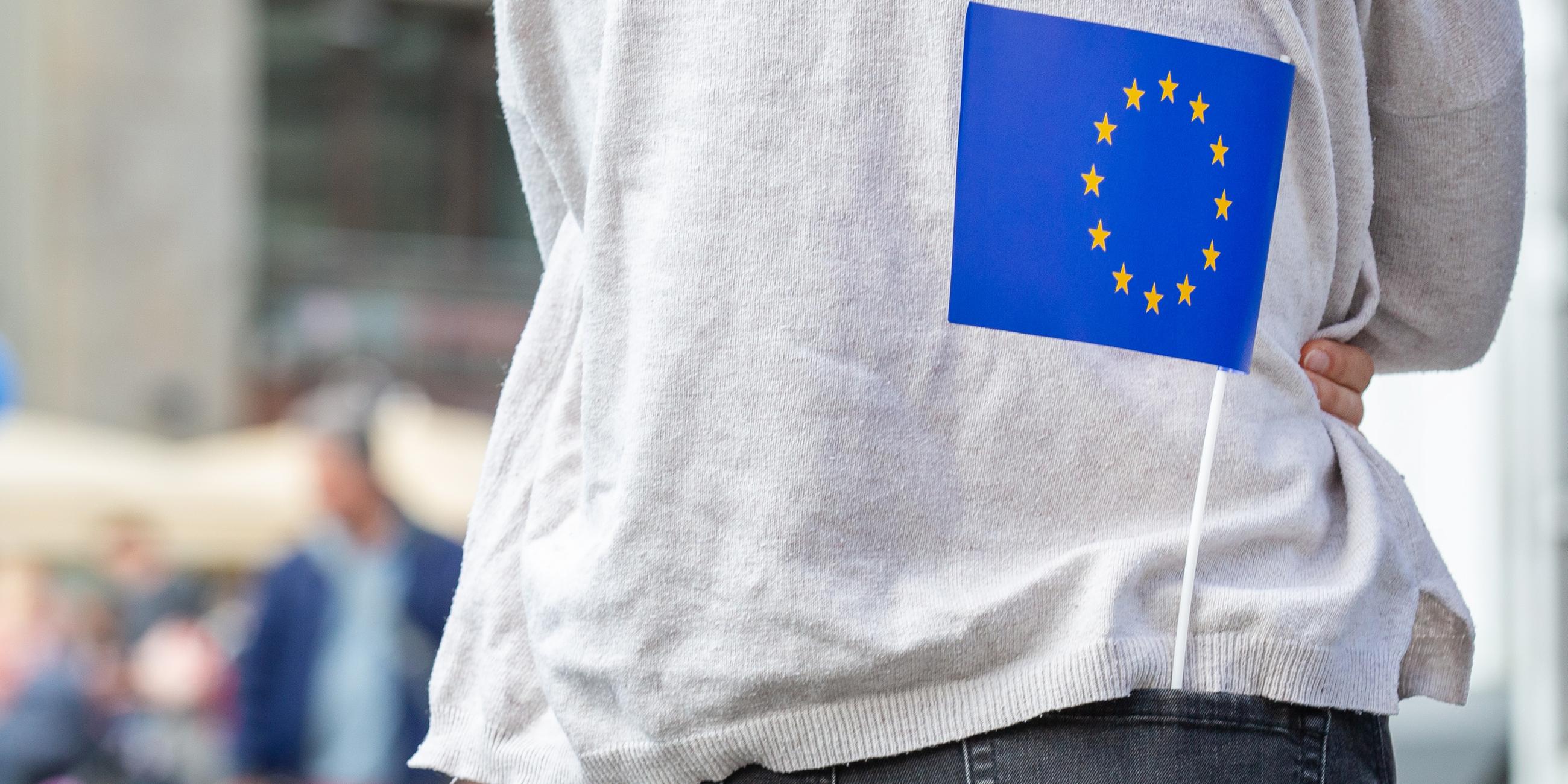 Eine kleine Europa-Flagge steckt in der Hosentasche eines Mädchens. 