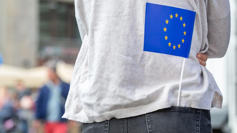 Eine kleine Europa-Flagge steckt in der Hosentasche eines Mädchens. 