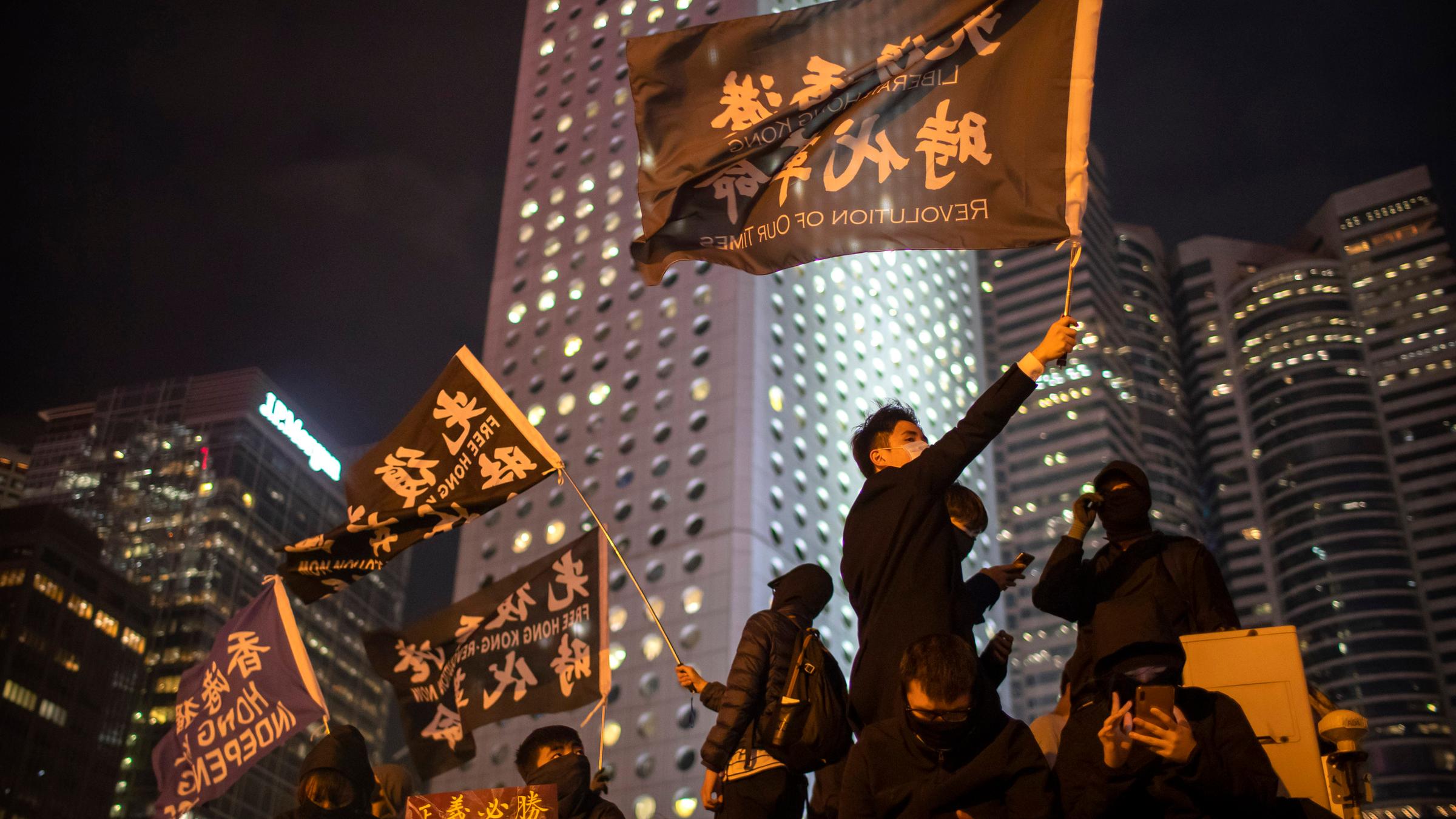 Menschen demonstrieren mit großen Fahnen auf den Straßen der Stadt Hongkong. 