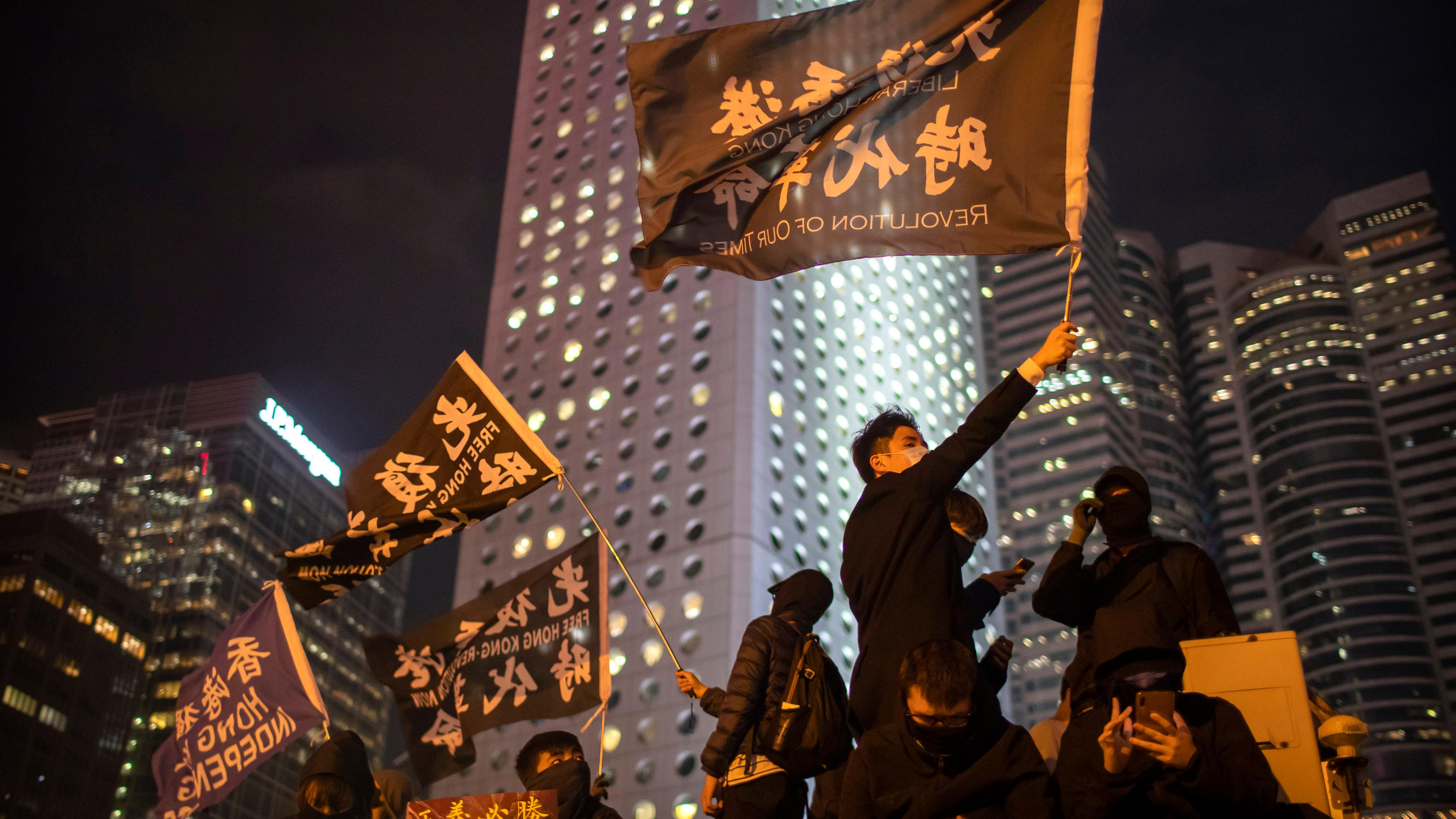Menschen demonstrieren mit großen Fahnen auf den Straßen der Stadt Hongkong. 