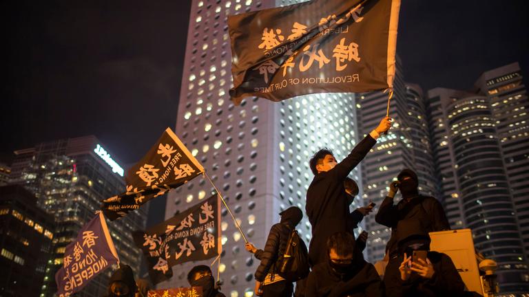 Menschen demonstrieren mit großen Fahnen auf den Straßen der Stadt Hongkong. 