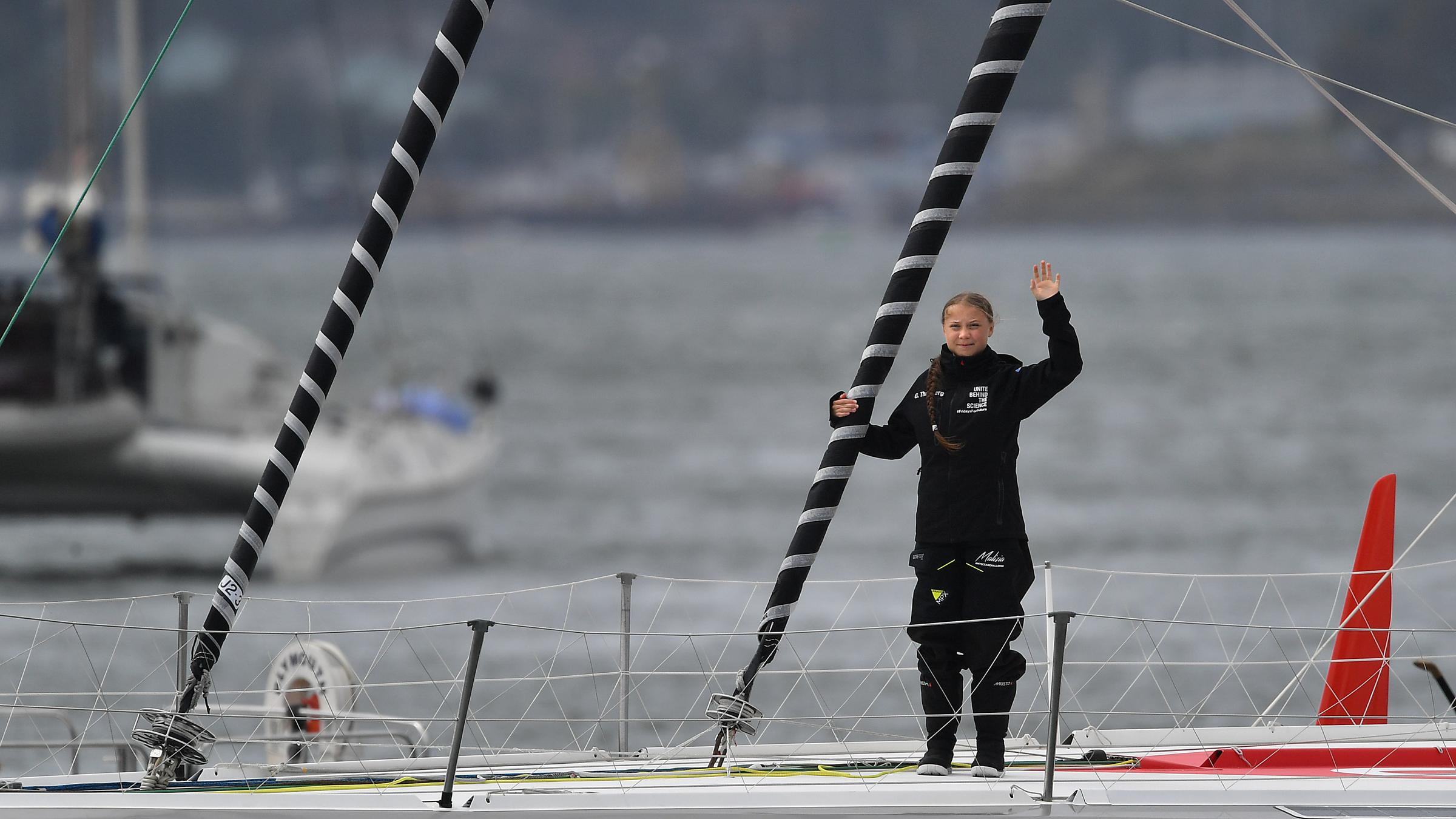 Greta Thunberg steht winkend auf einer Hochseejacht. 