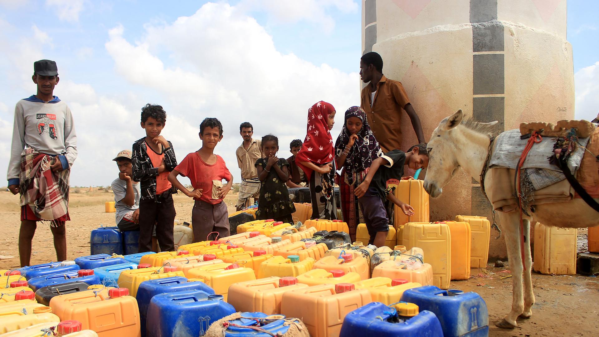 Jemenitische Kinder vor Wasserkanistern an einem Verteilungspunkt.
