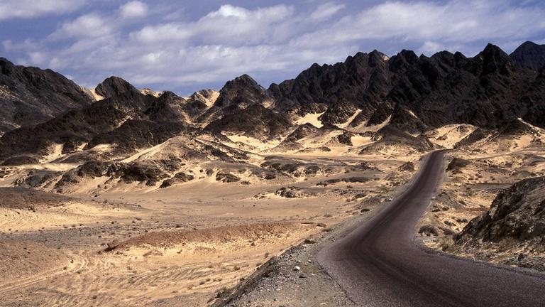 Straße im Jemen führt durch Vulkangestein und Sand