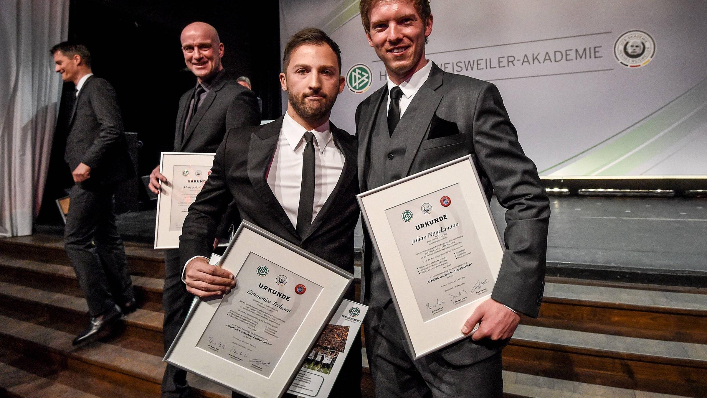 Julian Nagelsmann und Domenico Tedesco halten ihre Urkunden bei der Abschlussveranstaltzung zum Fussball-Lehrer-Lehrgang in die Kamera.