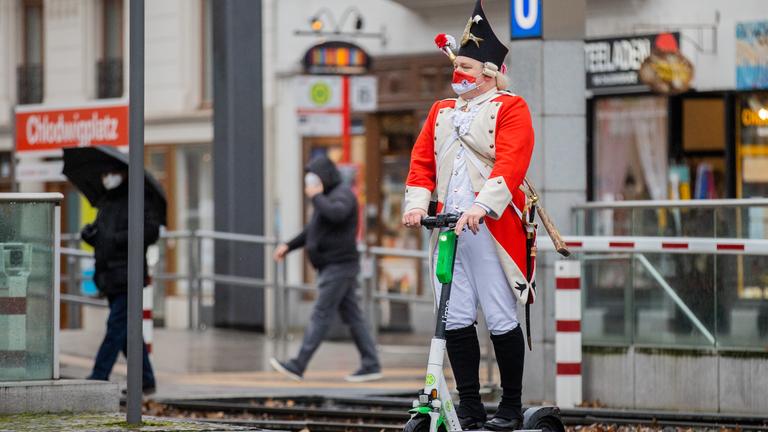 Ein Mann mit roter Pappnase läuft vor dem Kölner Dom.