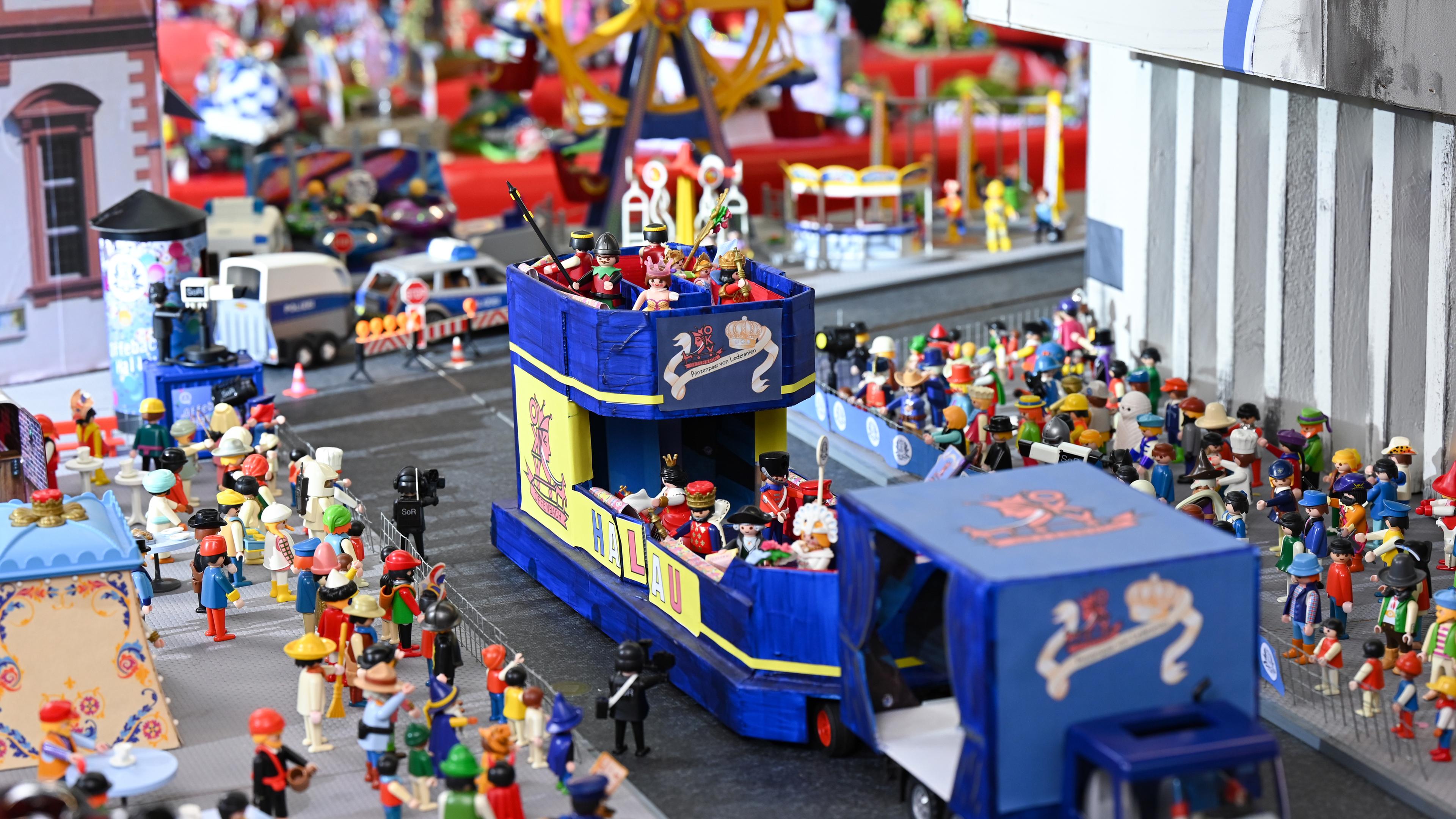 Ein blauer Spielzeug-Umzugswagen fährt zwischen Spielfiguren hindurch.