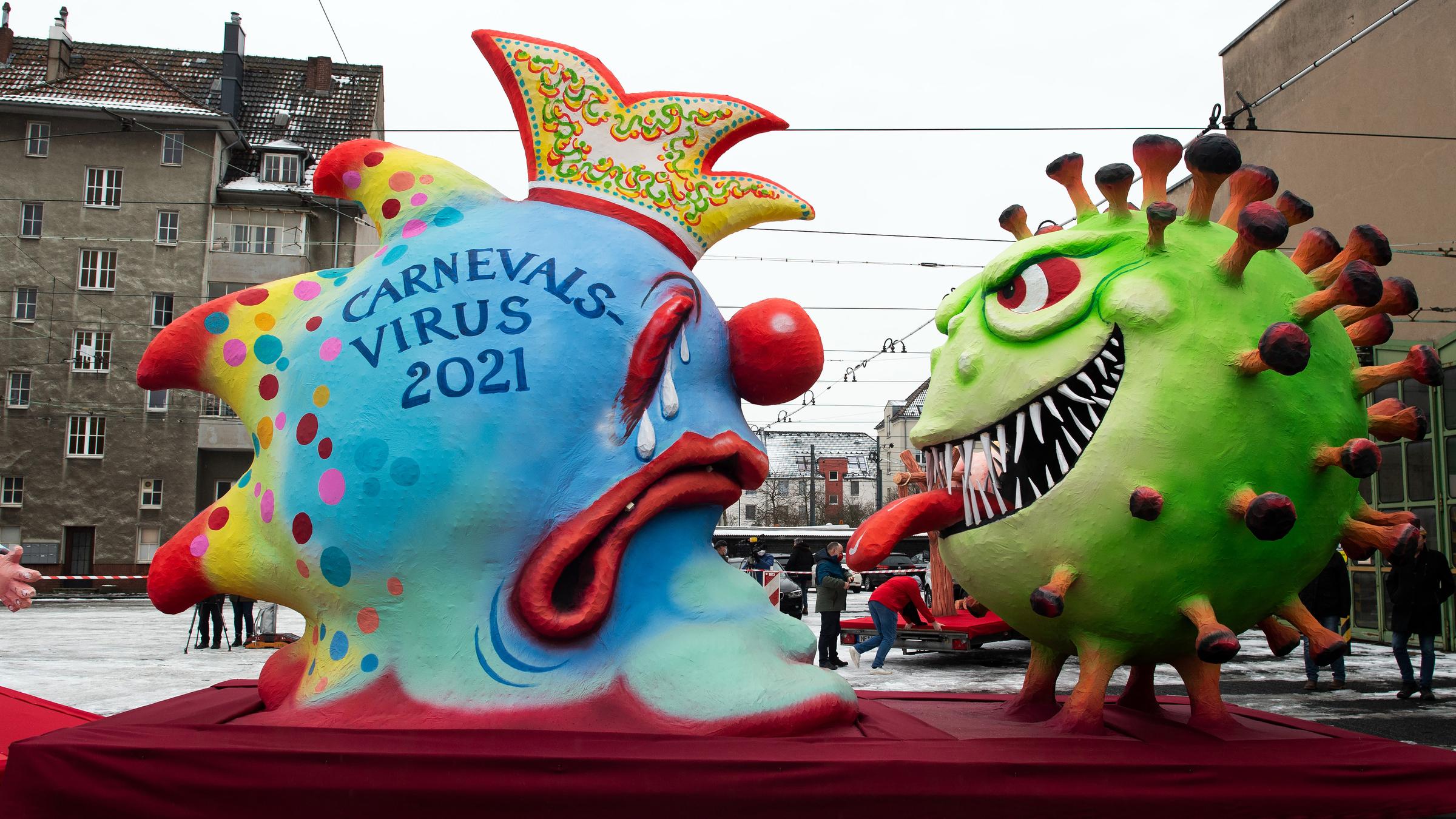 Auf einem Motto-Wagen stehen zwei Viren als riesige Figuren gegeneinander. Einer hat die Aufschrift "Carnevalsvirus 2021", der andere soll einen Coronavirus darstellen.