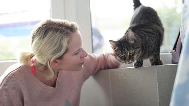 Eine Frau streichelt eine getigerte Katze