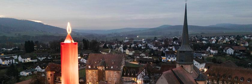 Die 42-Meter hohe Kerze leuchtet zwischen den Fachwerkhäusern der Altstadt im hessischen Vogelsbergkreis (Luftaufnahme mit einer Drohne). Unter dem roten Tuch verbirgt sich ein mittelalterlicher Turm, der von weitem sichtbar ist.