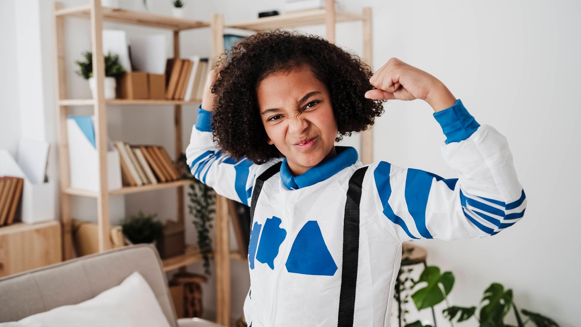 Mädchen in Superheldenkostüm zeigt Bizeps 