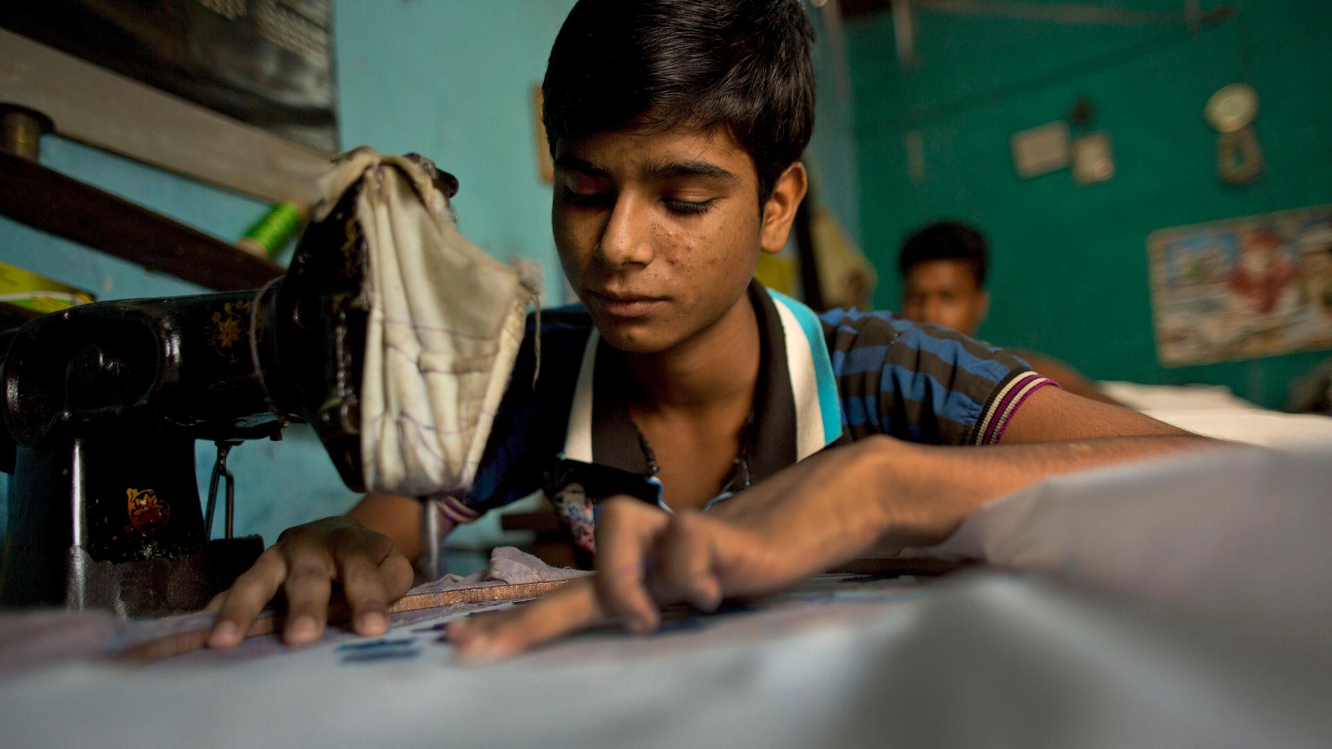 Ein Junge näht an einer Nähmaschine