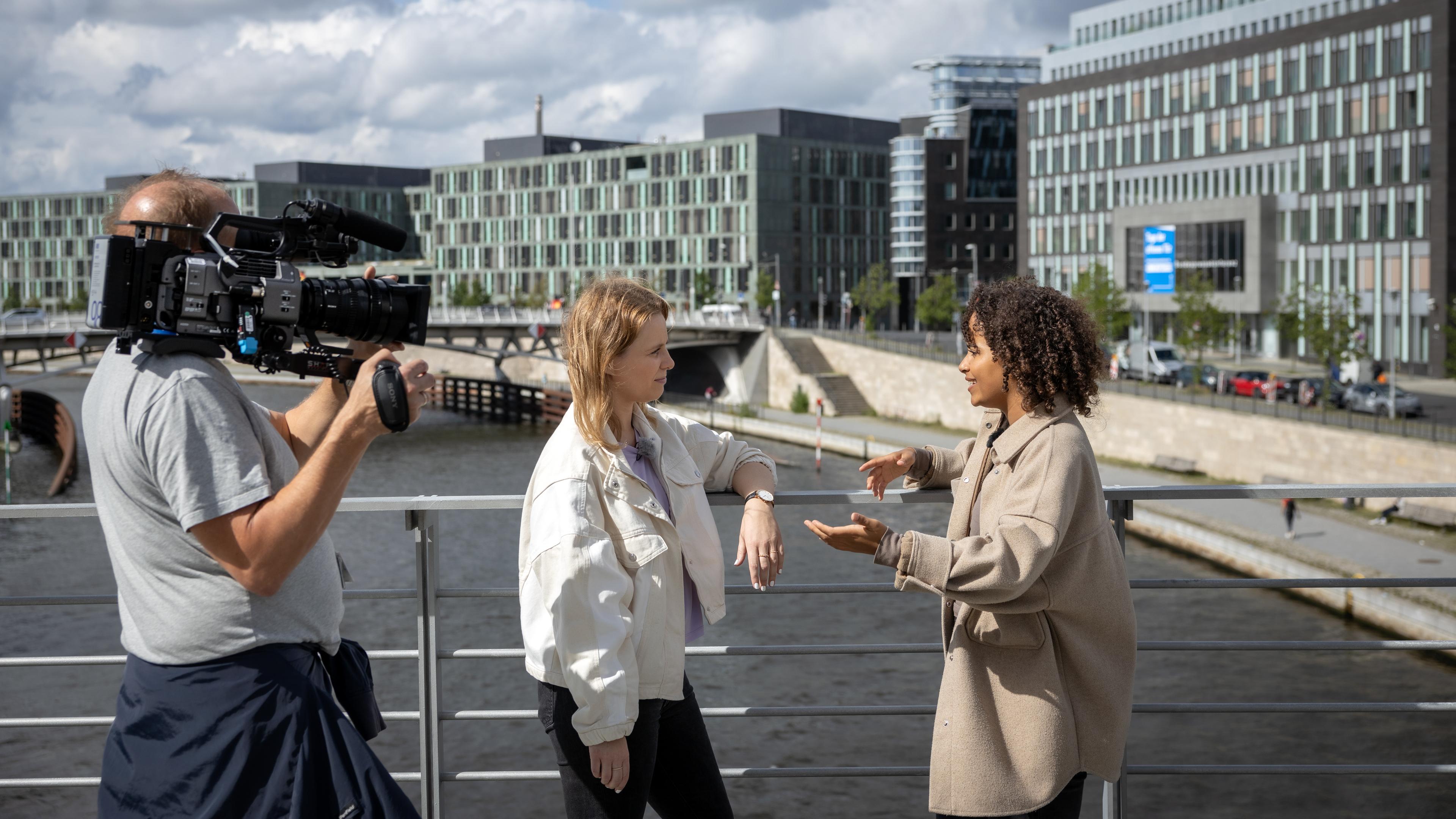 Linda interviewt Frau, Kameramann filmt sie