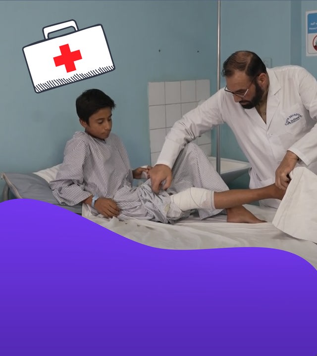 Ein Mann versorgt einen Jungen auf einer Liege in einem Krankenhauszimmer.