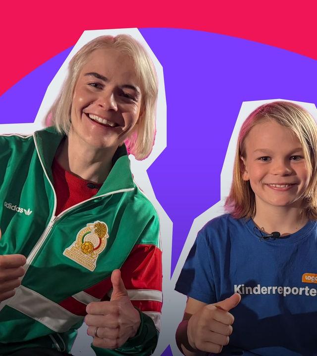Ein Junge sitzt neben Hazel Brugger, sie lachen in die Kamera. 