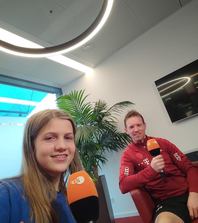 logo!-Kinderreporterin Antonia und Julian Nagelsmann lächeln in die Kamera 