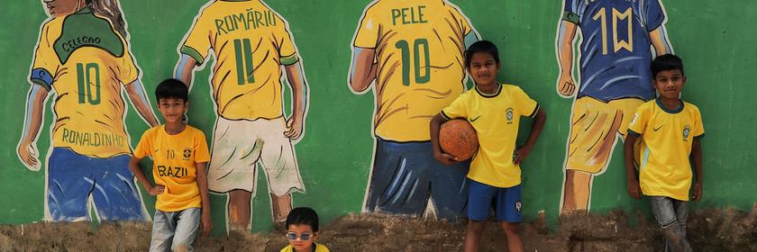 Kinder posieren vor Wandgemälden mit Motiven zur FIFA-Weltmeisterschaft, die an den Wänden des Stadtteils Bahaddarhat Khatib Para in Chattogram, Bangladesch, zu sehen sind.