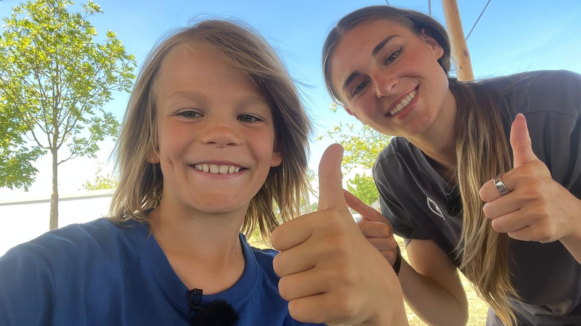 Fußballnationalspielerin Jule Brand posiert mit Kinderreporter Oskar