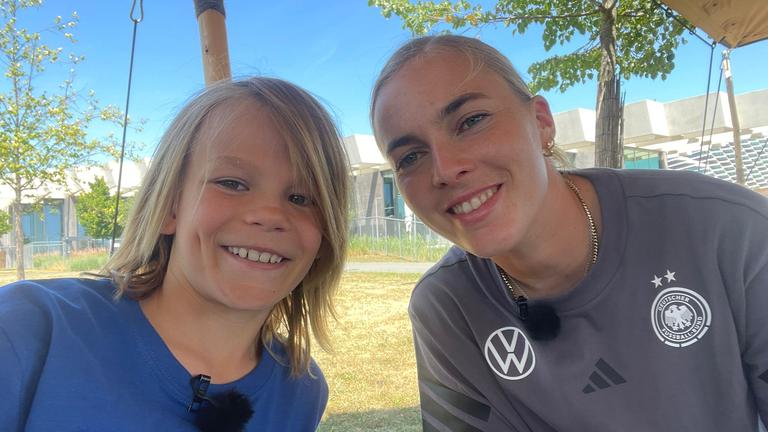 Fußballnationalspielerin Laura Freigang posiert mit Kinderreporter Oskar