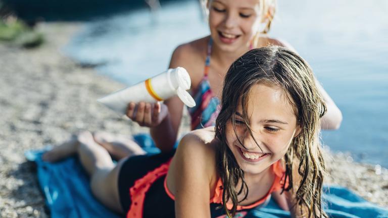 Zwei Mädchen cremen sich mit Sonnencreme ein