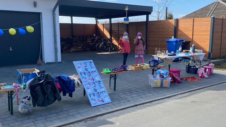 Zwei Mädchen verkaufen Kuchen und machen Flohmarkt für Spenden