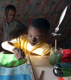 Drei Jungs an einem Tisch, einer malt ein Bild mit blauen und grünen Farben. 