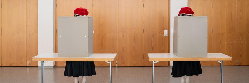 Zwei Frauen stehen in ihrer traditionellen Schwarzwälder Tracht mit rotem Bollenhut im Wahllokal und geben ihre Stimme für die Landtagswahl ab.