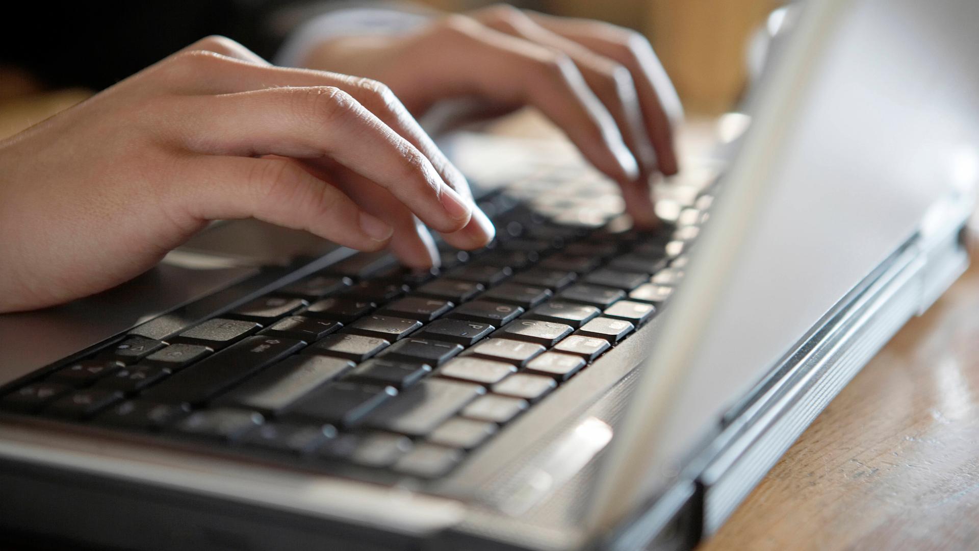 Hand an einer Laptop-Tastatur