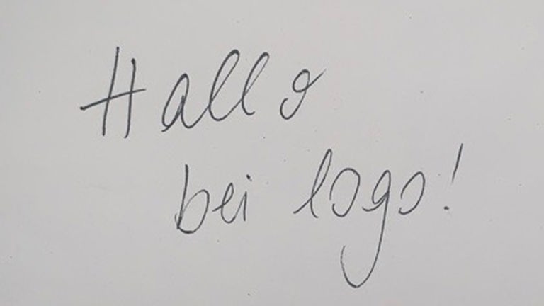 Weißer Zettel mit Handschrift "Hallo bei logo!"