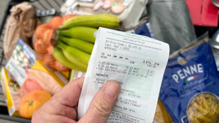 Mann kontrolliert Kassenzettel vor dem Einkaufswagen