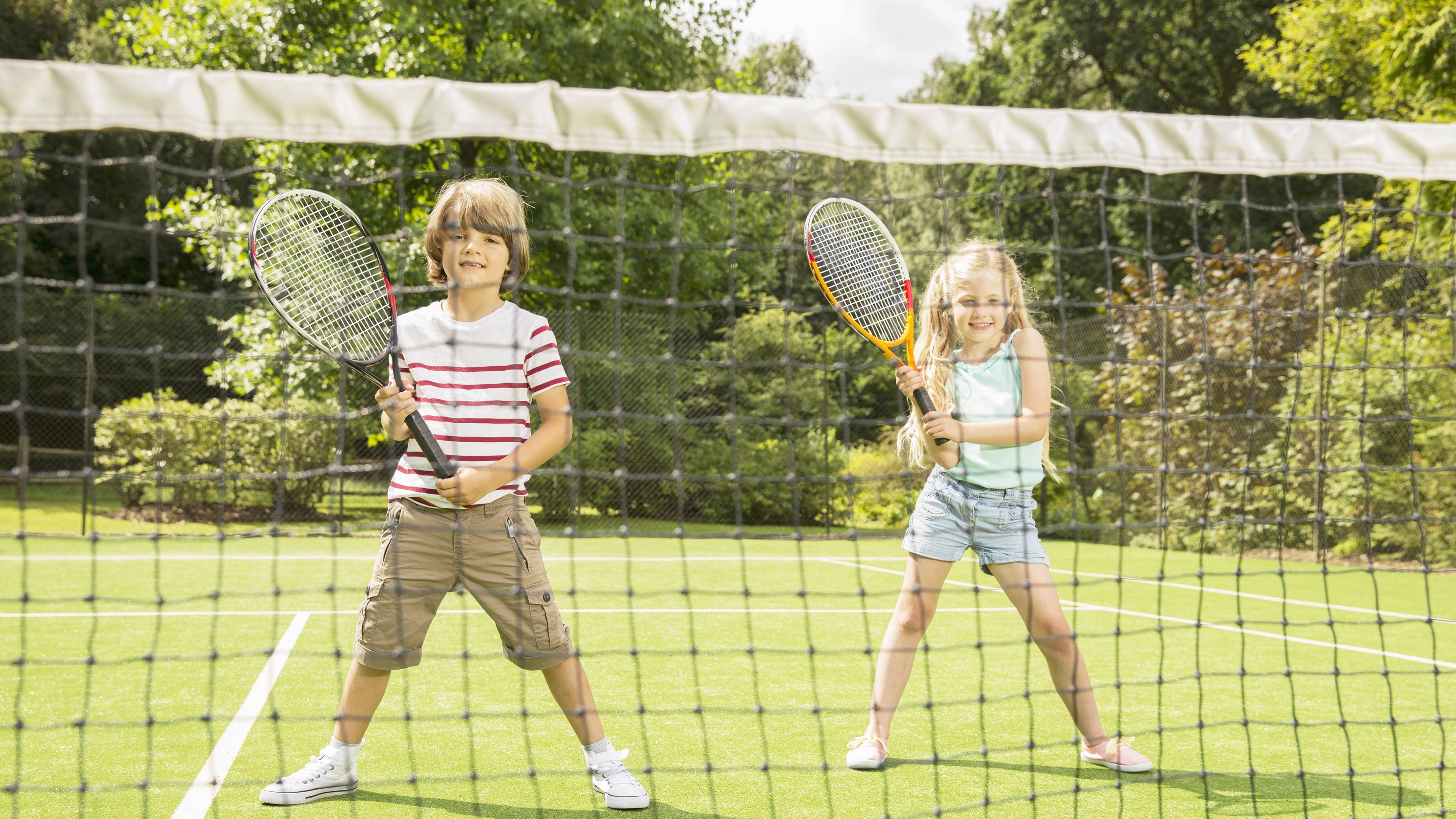Junge und Mädchen auf dem Tennisplatz 
