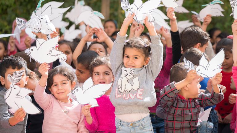 Die schönsten Weihanchts-Hits: Kinder halten Friedenstauben aus Papier in den Händen