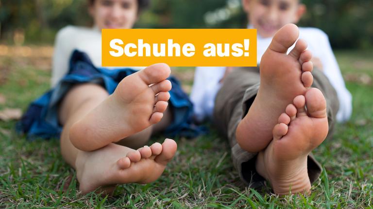 Zwei Kinder strecken ihre Füße aus, darüber steht auf gelbem Hintergrund Schuhe aus!
