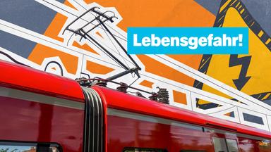 Ein Zug fährt unter der Oberleitung entlang zu lesen ist Lebensgefahr dahinter ist ein Warnschild zu sehen