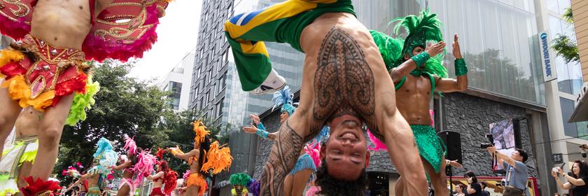 Ein Tänzer trägt eine Hose in den Farben der brasilianischen Flagge und macht auf einer Straße in Seoul einen Handstand. 